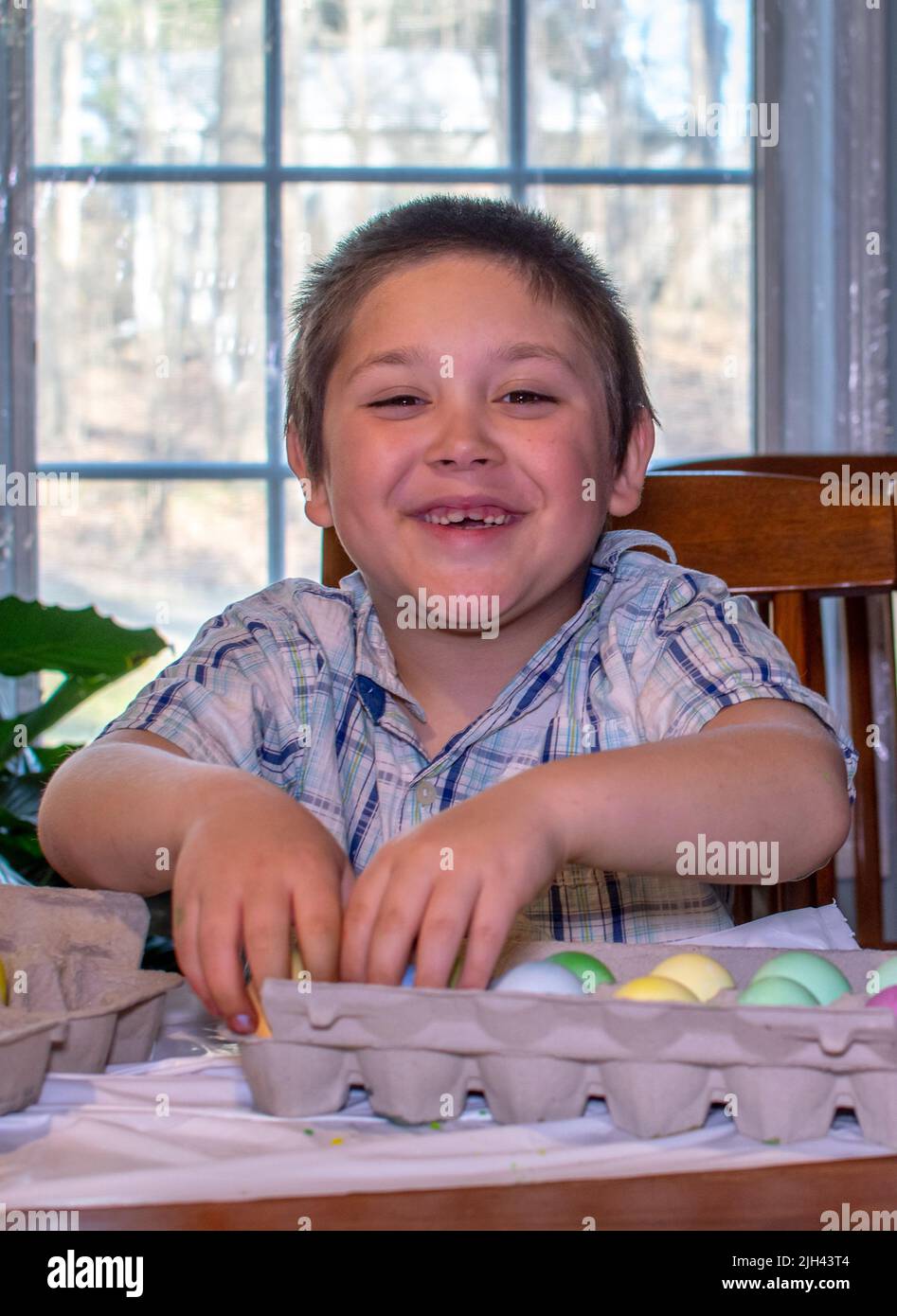 il ragazzo sorridente mostra con orgoglio le sue colorate uova di pasqua che ha appena tinto Foto Stock