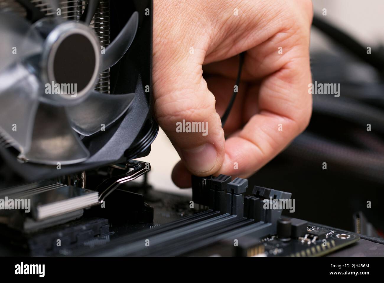 Tecnico che collega il cavo patch dal dissipatore di calore in alluminio raffreddato ad aria al processore Foto Stock