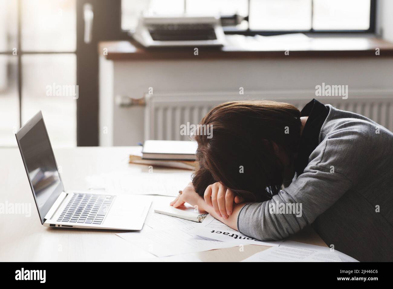 Giovane donna stanca che dorme alla scrivania dell'ufficio Foto Stock