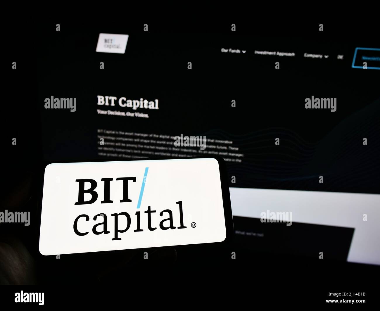 Persona che tiene uno smartphone con il logo della società finanziaria tedesca BIT Capital GmbH sullo schermo di fronte al sito web. Mettere a fuoco sul display del telefono. Foto Stock