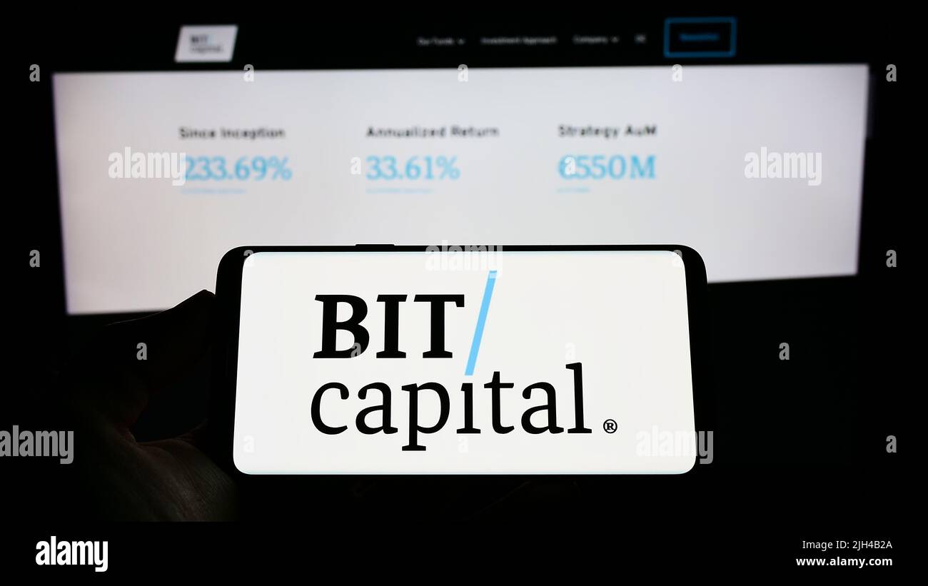 Persona che detiene il cellulare con il logo della società finanziaria tedesca BIT Capital GmbH sullo schermo di fronte al sito web aziendale. Mettere a fuoco sul display del telefono. Foto Stock