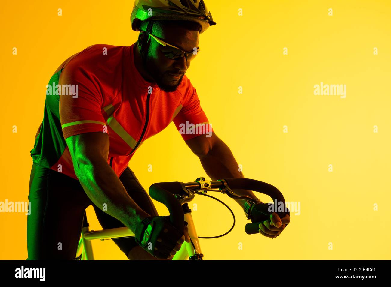 Immagine di ciclista maschile afroamericana in bicicletta con illuminazione gialla Foto Stock