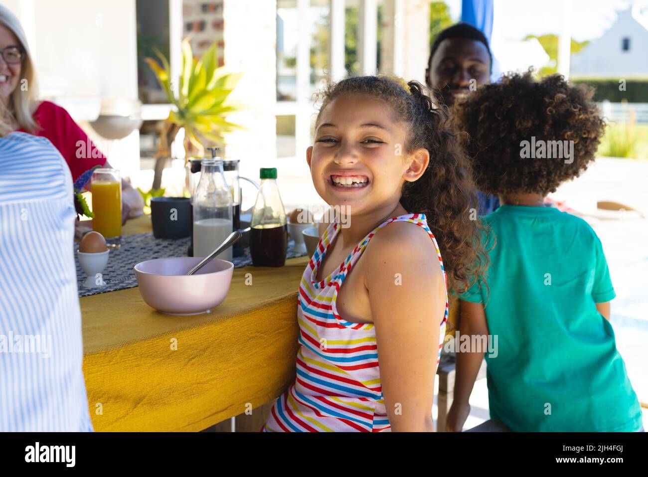 Ritratto di sorridente ragazza carina multigenerazione facendo colazione con la famiglia al tavolo da pranzo a casa Foto Stock