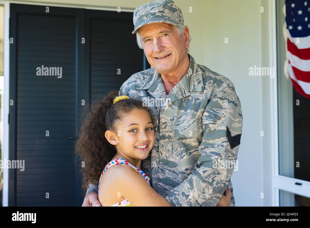 Ritratto di sorridente nonno militare multirazziale in abbigliamento camouflage abbracciando la nipote Foto Stock