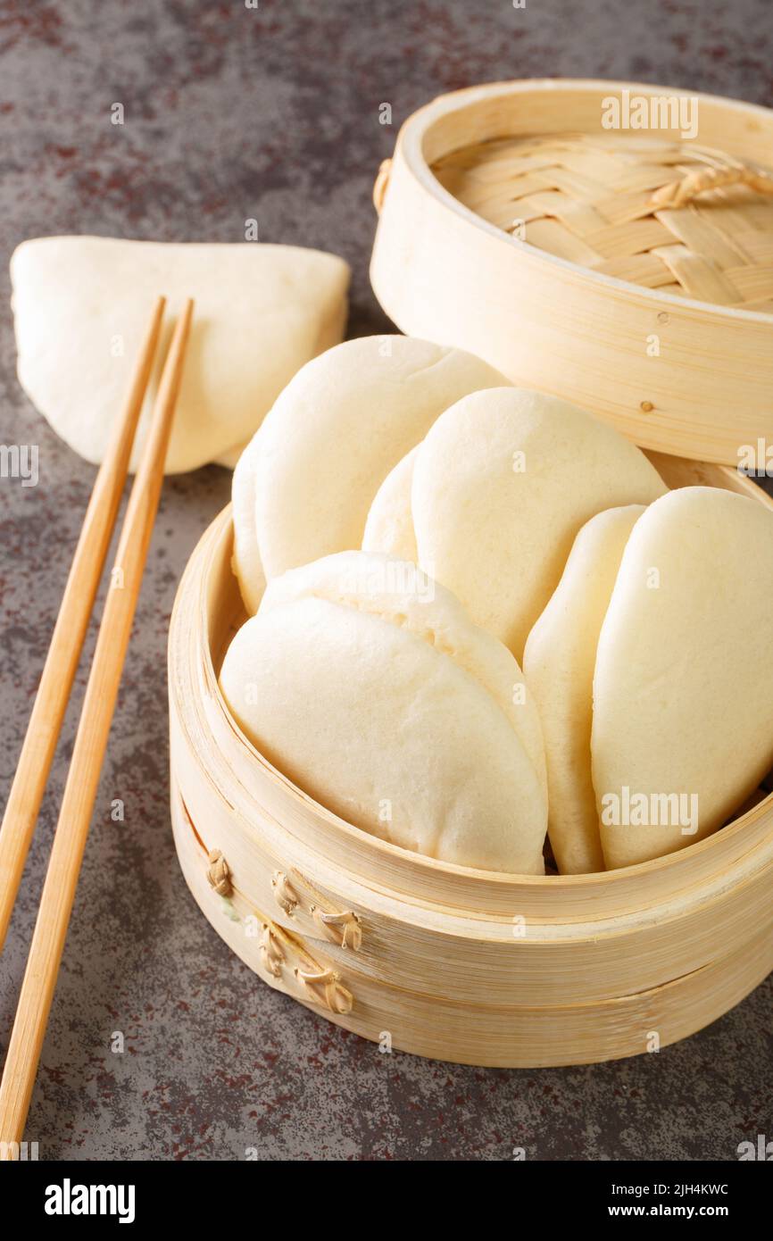 Primo piano la foglia di Bao Buns al vapore sul cesto di bambù sul tavolo. Verticale Foto Stock