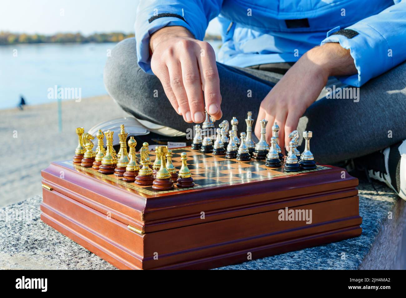 Un giovane si siede a zampe incrociate e gioca a scacchi nel parco sul lungomare. Primo piano. Foto Stock