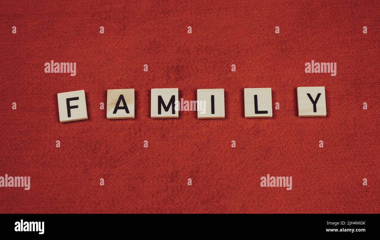 Parola 'Famiglia' composta da piastrelle di legno con lettere su sfondo rosso Foto Stock