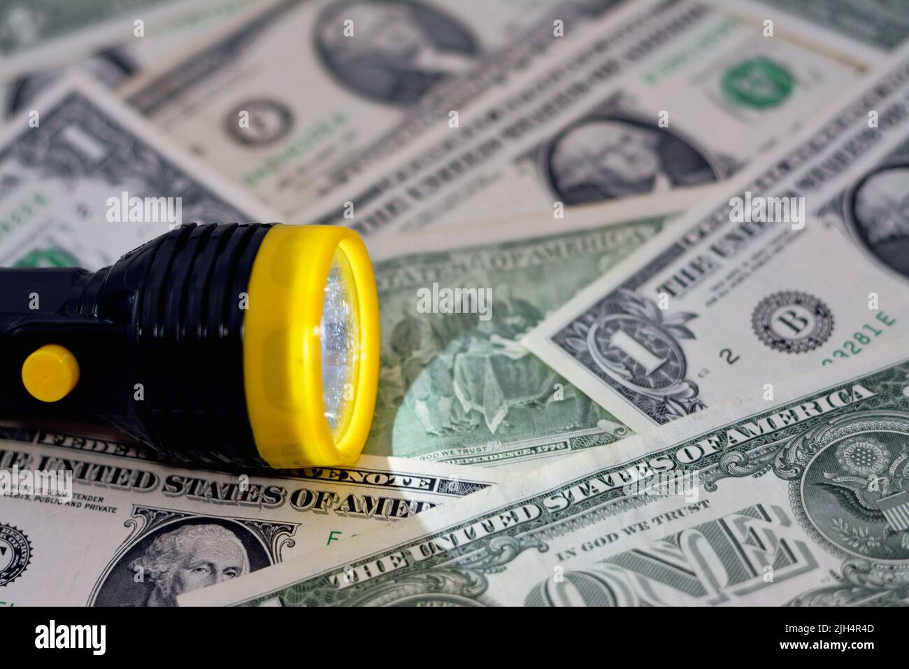 Una torcia gialla e nera con una luce LED su uno sfondo sfocato della valuta delle banconote in denaro americane, dollari USA in un fuoco selettivo con un t Foto Stock