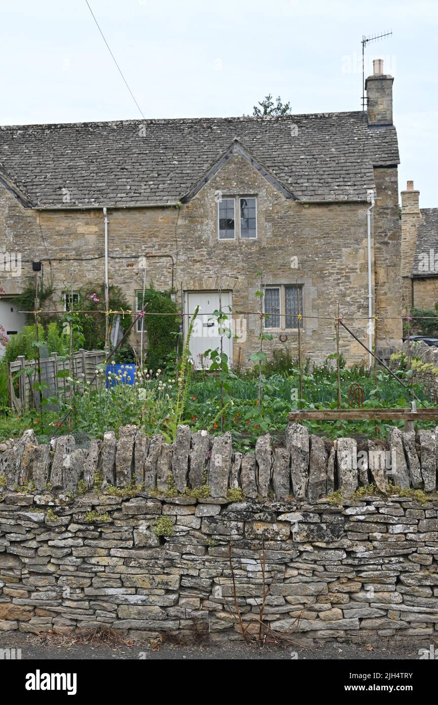 Un cottage nel villaggio Gloucestershire di Upper Slaughter mostra fuori il gaden anteriore che contiene una varietà di piante, tra cui piselli dolci in fiore Foto Stock