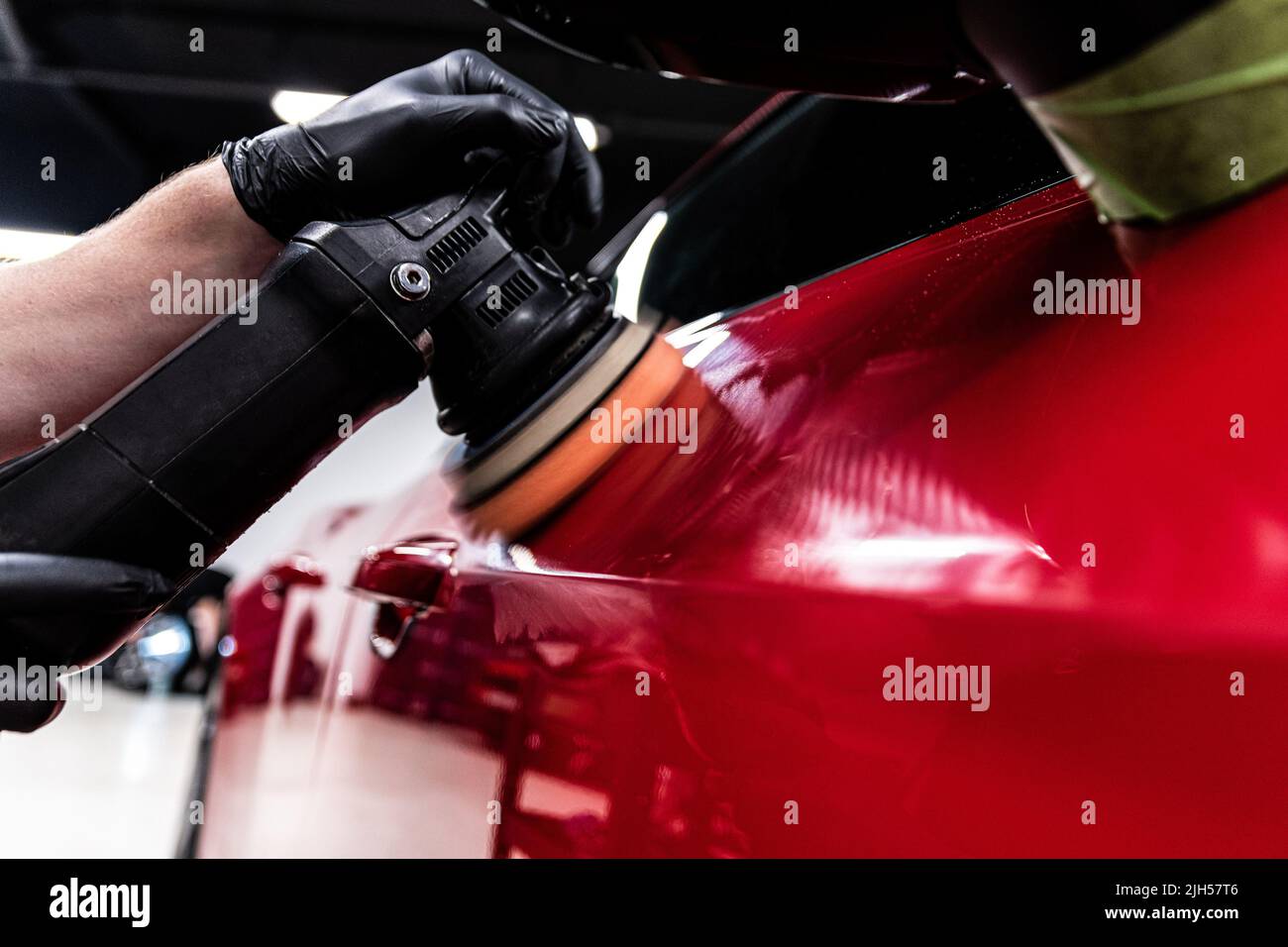 Impiegato di un lavaggio di automobile o di un studio di dettaglio di automobile lucida la vernice di automobile Foto Stock