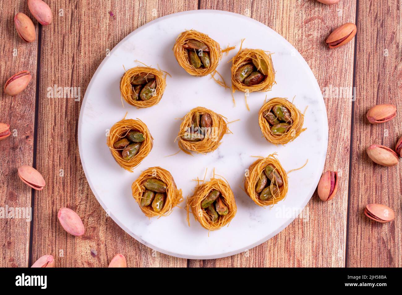 Bulbul Kadayif con Pistacchio. Kadayif baklava con riempimento di pistacchio su un pavimento di legno. Dessert di cucina turca. Primo piano. Nome locale Antep Fıstıklı Foto Stock