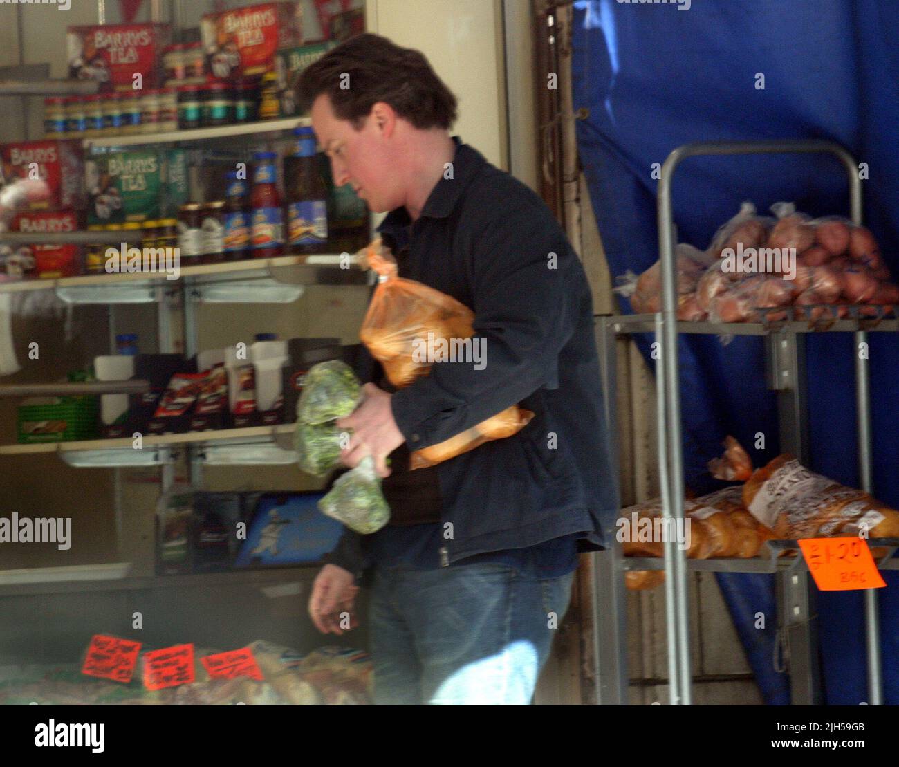 David Cameron è chiaramente un uomo della sua parola come egli usa la sua moto per fare la famiglia a fare la spesa presso i suoi negozi locali. Chiaramente non è per il sig. Cameron è il 'celebrità stile' supermercato consegne di stile come il 'moderne man' carichi la sua bicicletta in un vero sinistra/destra bilanciamento atto come egli ruotata a destra di fronte un juuggernaut! La prossima volta forse un insieme di ciclismo ingranaggio di sicurezza potrebbe essere appropriato. Foto di Tony Henshaw Foto Stock