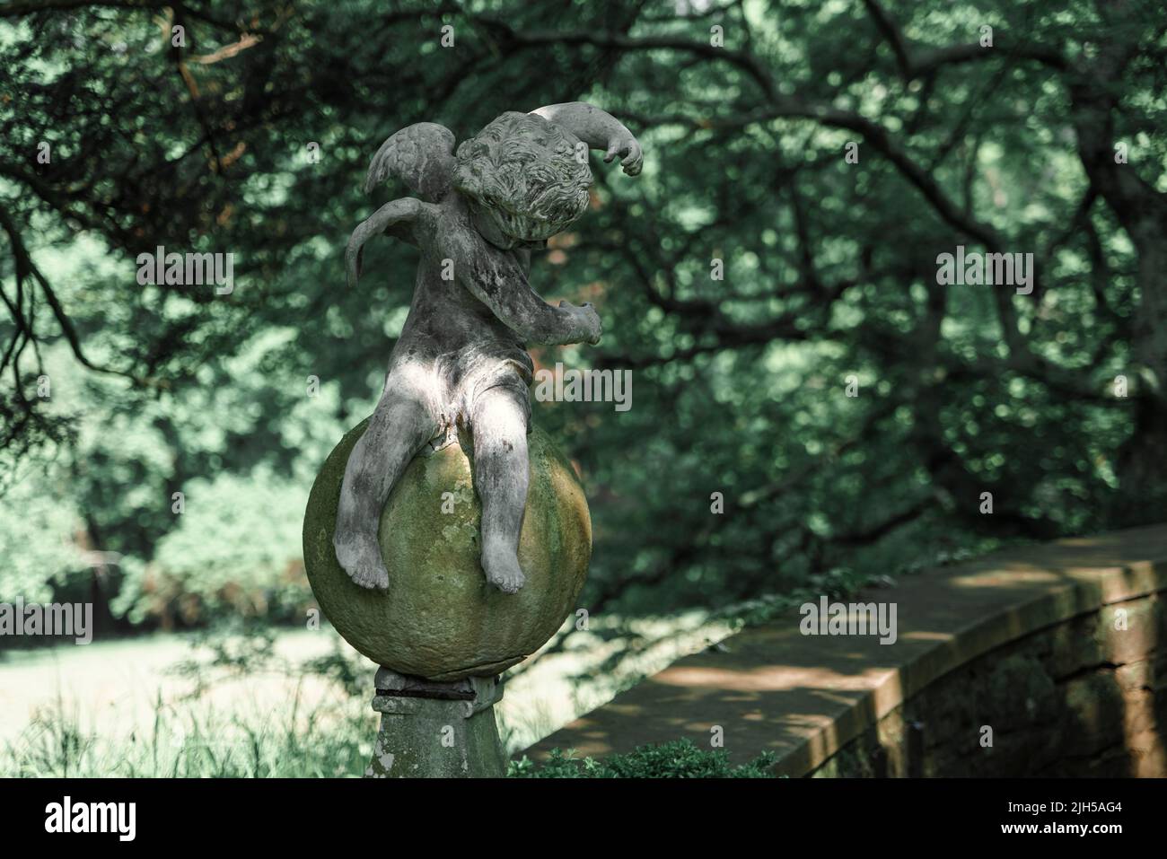 Scultura in ceramica di un piccolo Angelo seduto in un giardino botanico del New Jersey. Foto Stock