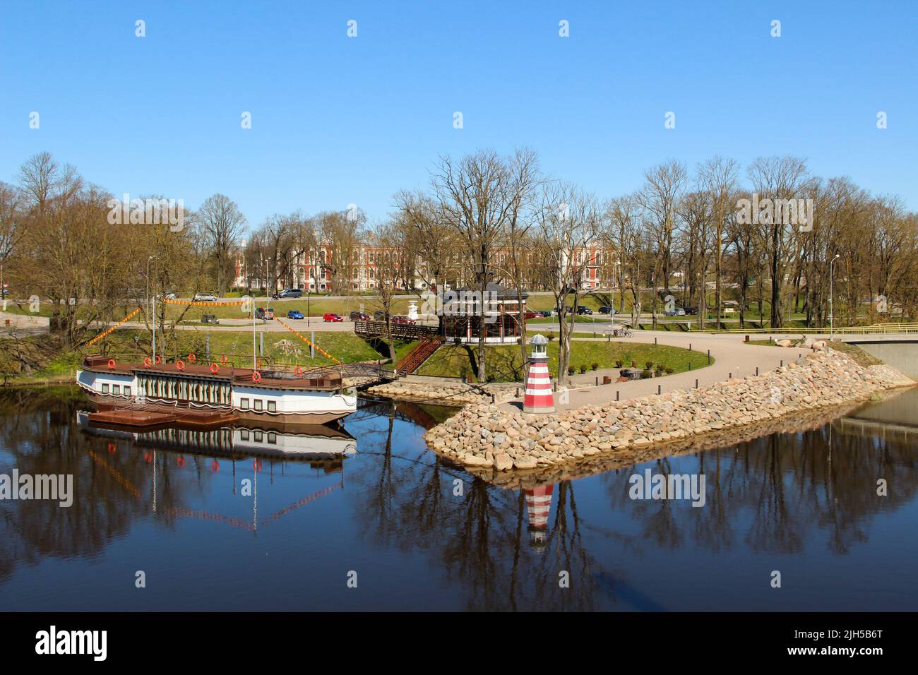 Canale cittadino con faro decorativo e nave a vapore sulla costa. Popolare paesaggio acquatico nella città di Jelgava. Foto Stock