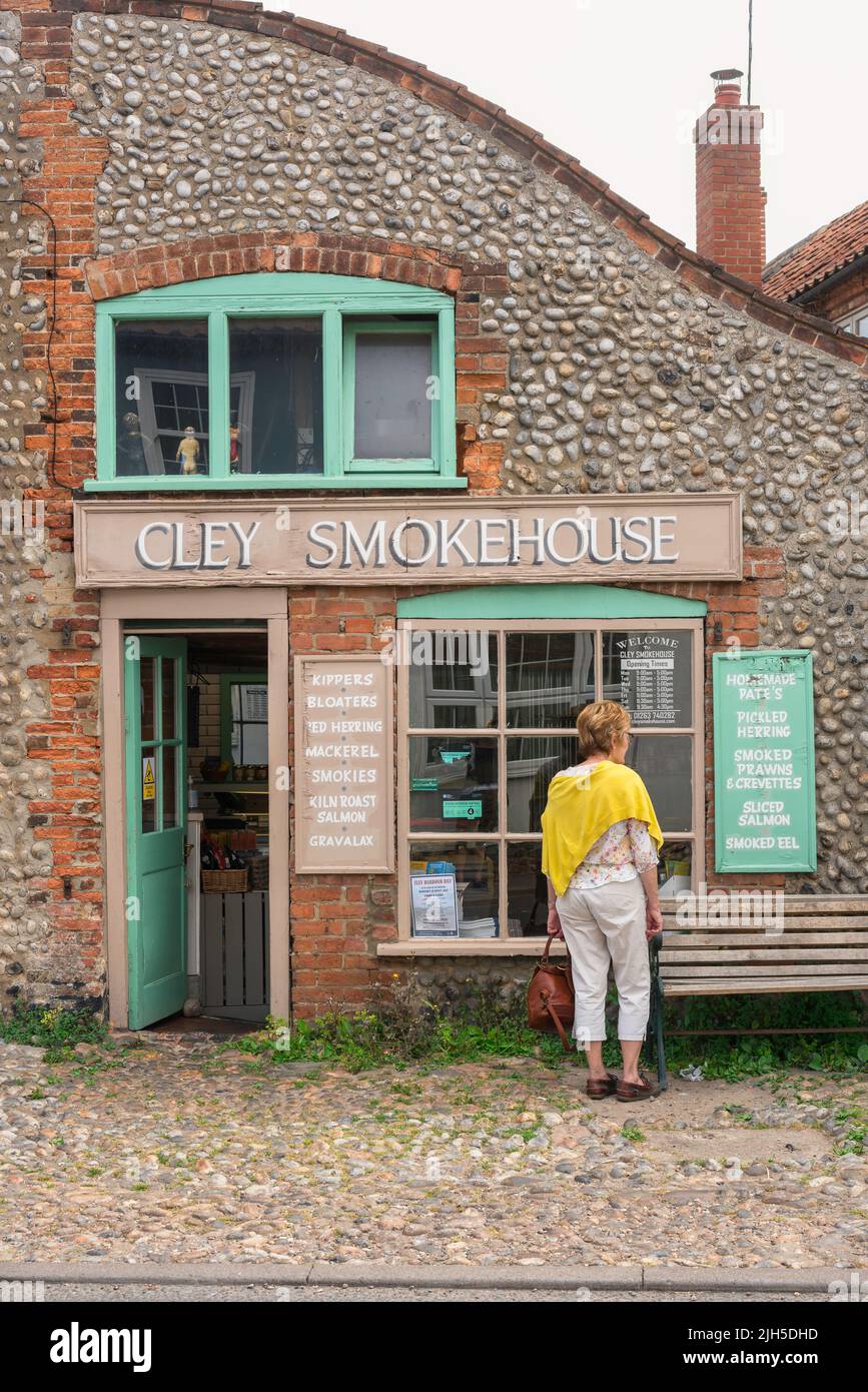 Cley accanto al mare Smokehouse, vista di una donna visitatore di Cley accanto al mare guardando nella finestra del Cley Smokehouse, costa nord norfolk, Inghilterra Foto Stock