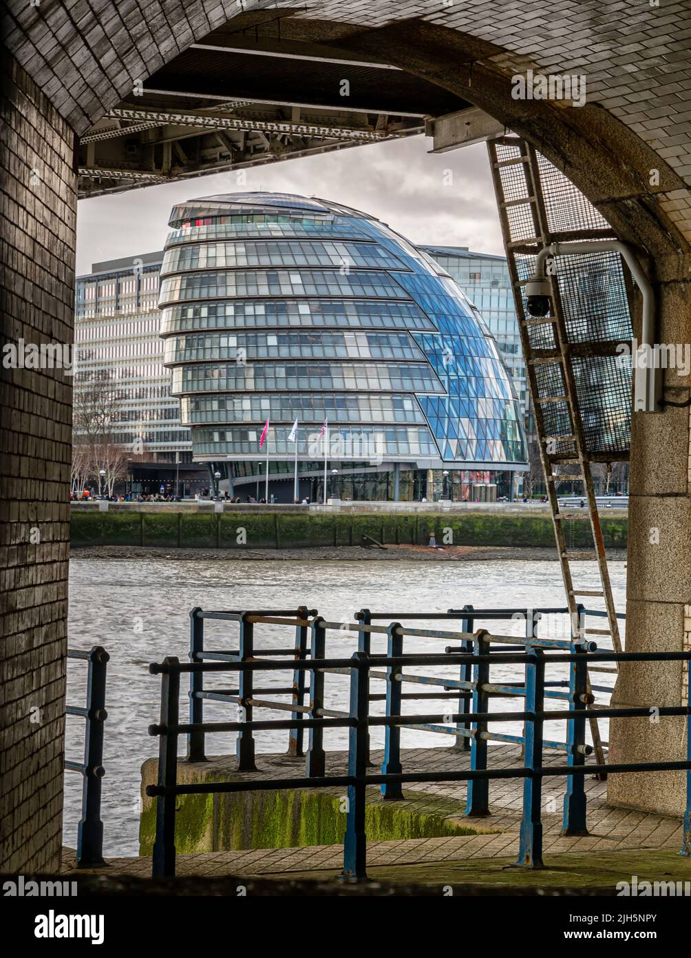 City Hall visto attraverso e incorniciato dai gradini lungo il fiume di Tower Bridge, Londra Foto Stock