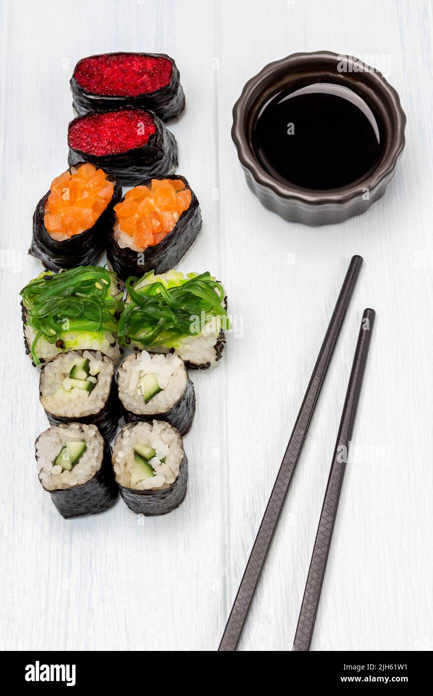 Set di sushi e salsa di soia in una ciotola, bacchette. Disposizione piatta. Sfondo bianco. Foto Stock