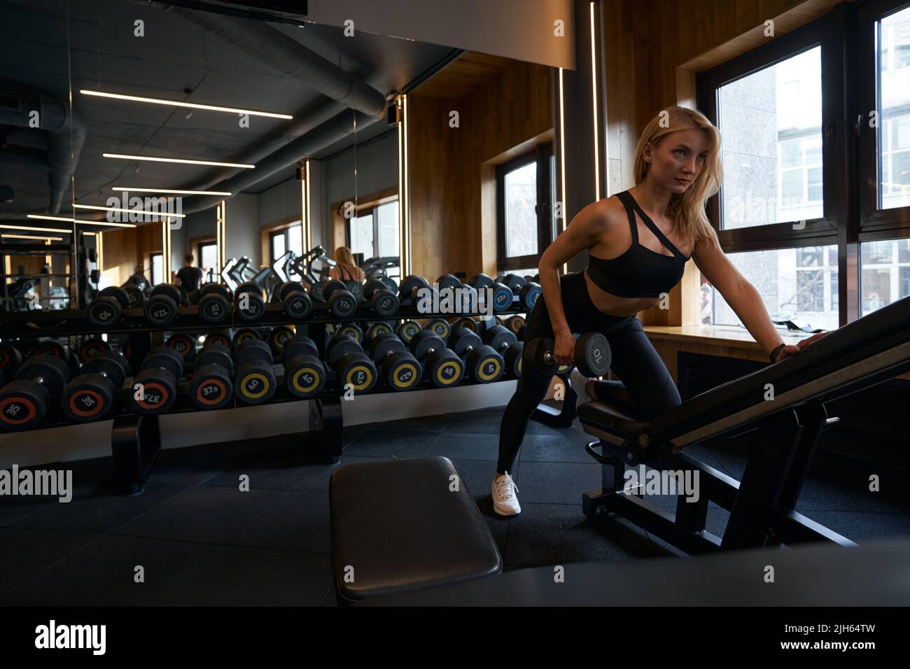 Sportivo che esegue fila ripiegata a braccio singolo nel fitness club Foto Stock