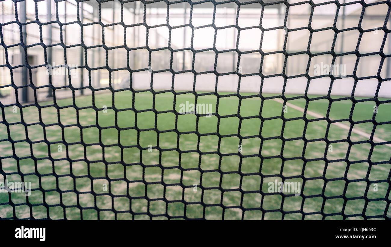 Rete e una parte di verde erba sintetica paddle campo da tennis al coperto senza persone. Paddle è un gioco di racquetball. Concetto sportivo professionale con copia spac Foto Stock