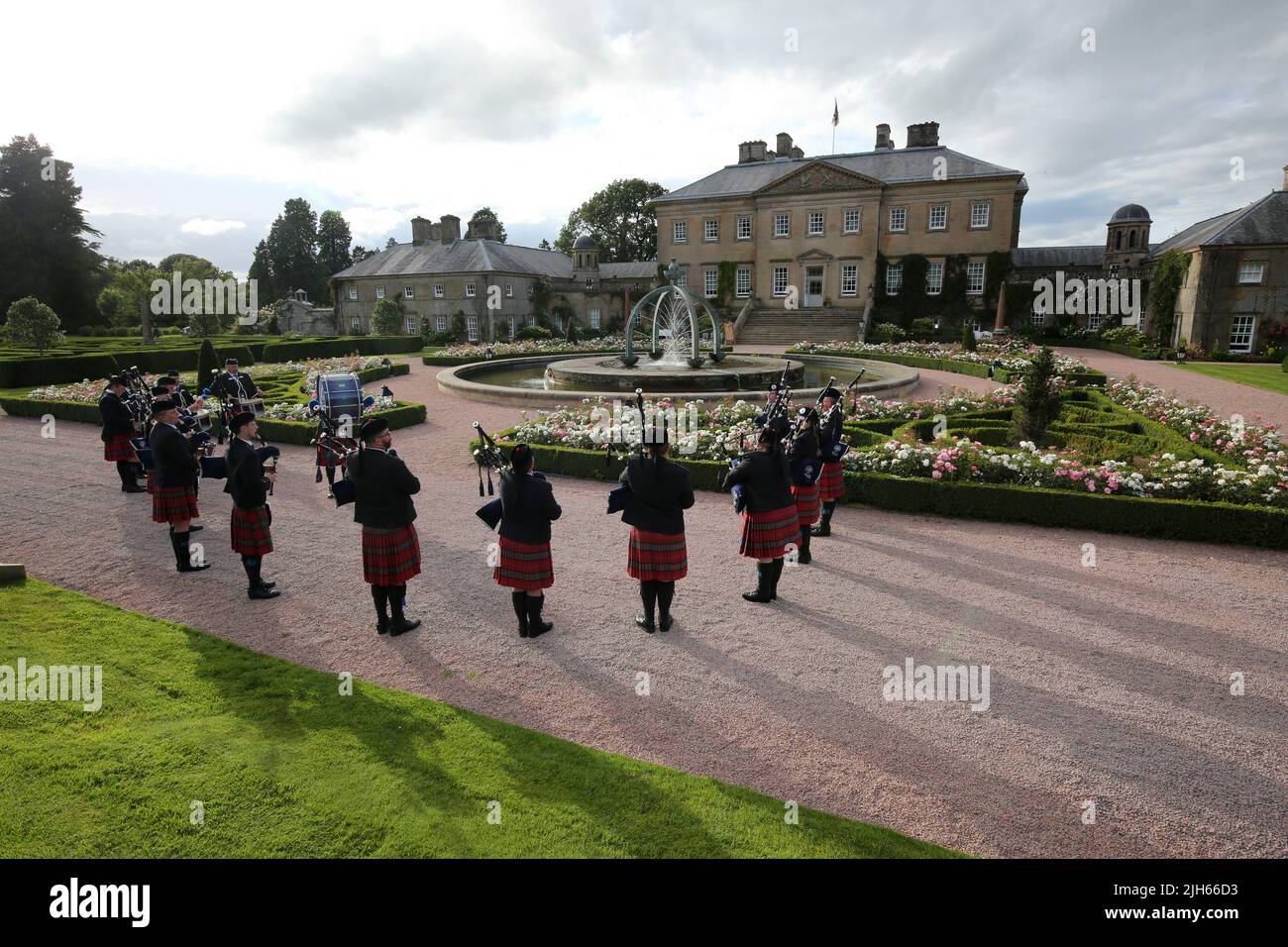 Dumfries House, Cumnock, Scotland UK, Ayr Pipe Band giocano di fronte alla casa. Indossando abiti tradizionali kilt e abbigliamento da testa glengarry. La fontana conosciuta come la Fontana di Mahfouz. Una peste vicina dice ' reso possibile dalla generosità di LUI Mahfouz Marei Murbank bin Mahfouz. ' La fontana fu formalmente opendita da S.R.H il Principe Carlo, Duca di Rothesay 21 ottobre 2014. Giardini formali circondano la fontana Foto Stock