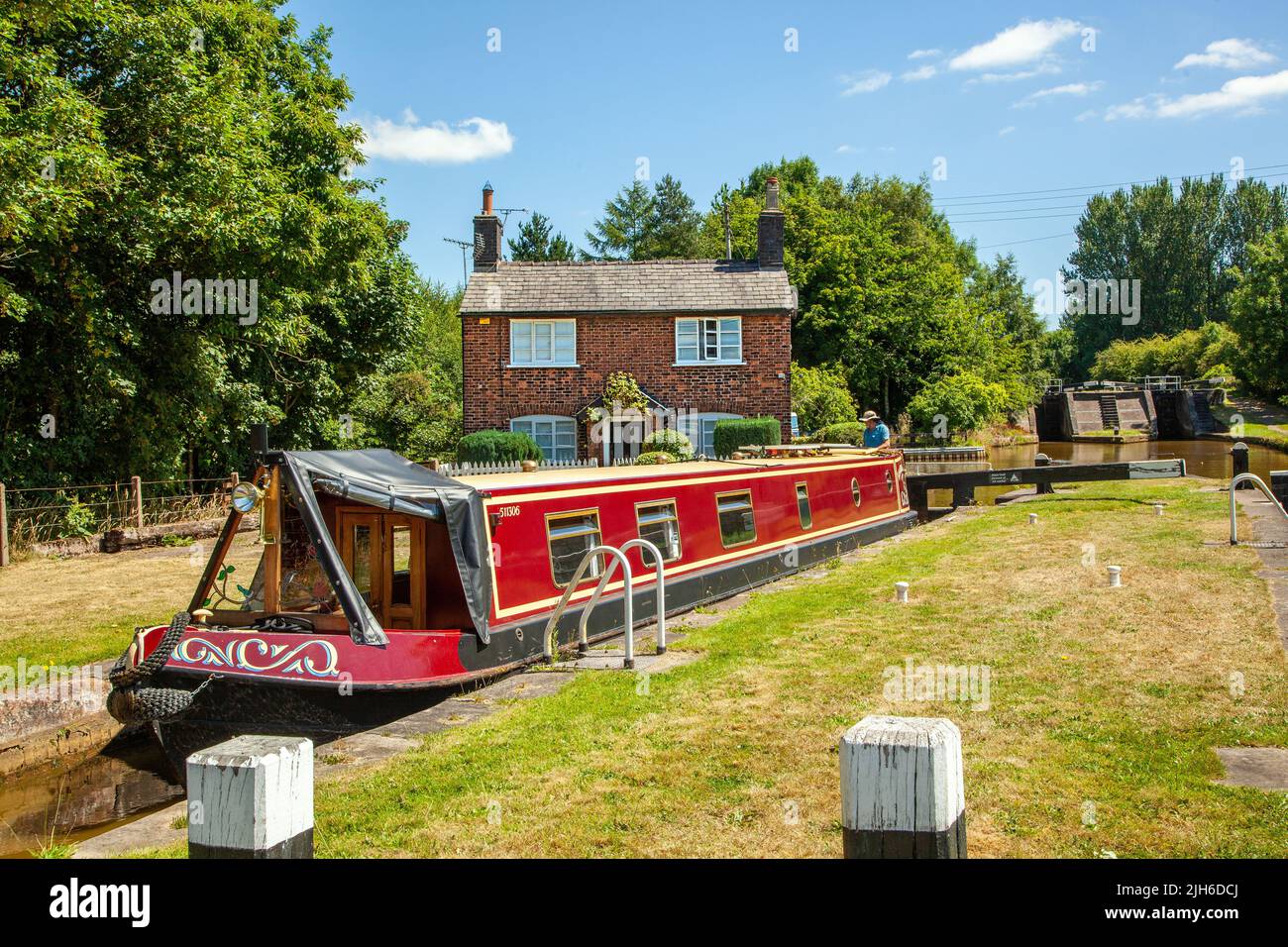 Canal narrowboat che passa attraverso chiuse sul canale Trent e Mersey mentre passa attraverso il villaggio di Wheelock Cheshire Inghilterra Foto Stock