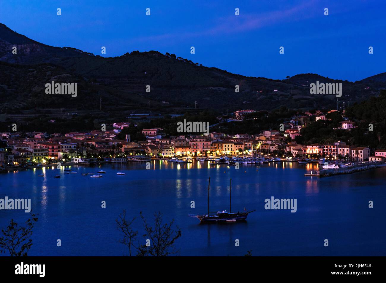 Vista di Porto Azzurro con passeggiata del porto illuminata di sera durante l'ora blu, Porto Azzurro, Elba, Toscana, Italia Foto Stock