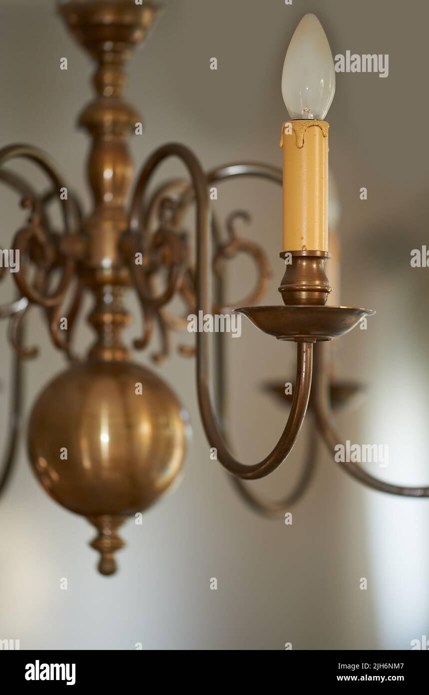 Primo piano di un lampadario in ottone d'epoca appeso come decorazione in un atrio, ingresso o sala da pranzo durante un oscuramento. Candela d'oro come l'illuminazione Foto Stock
