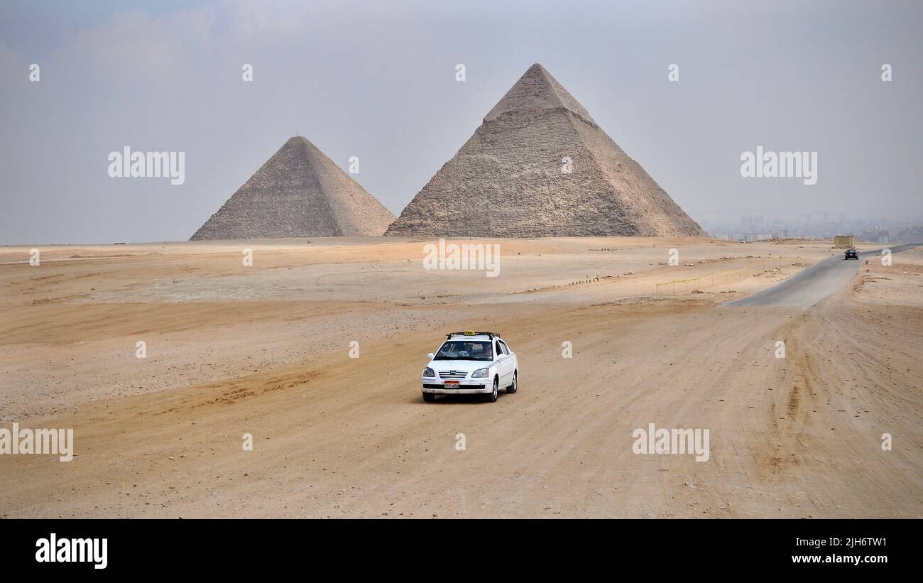 Un taxi passa davanti a due piramidi egiziane Foto Stock