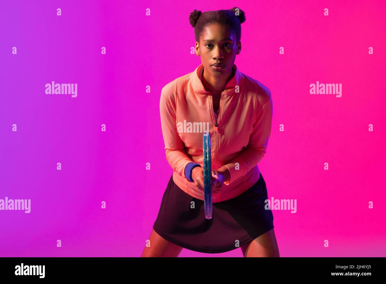 Immagine di una tennista afro-americana con illuminazione al neon viola e rosa Foto Stock