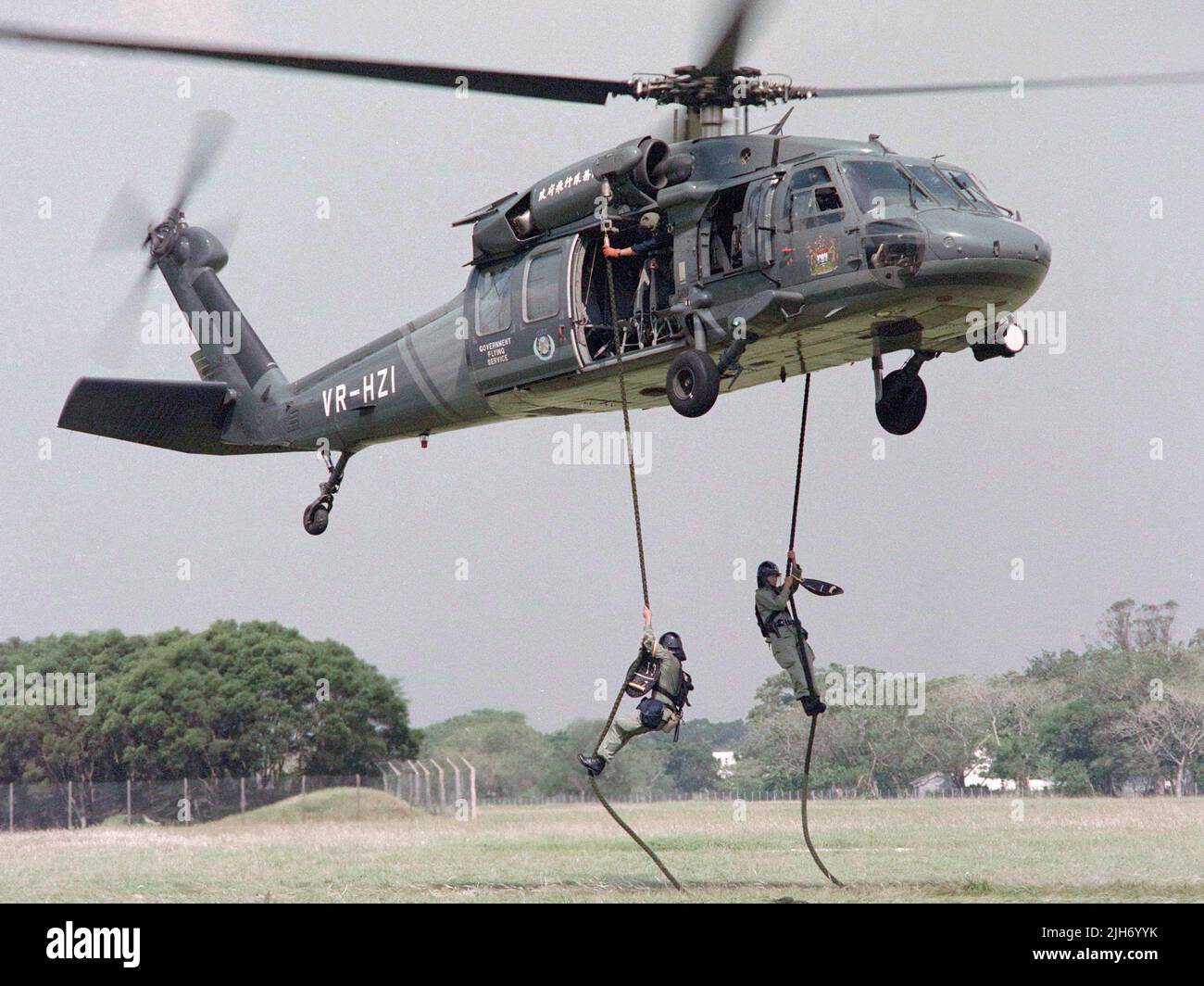 Unità tattica di polizia, (polizia reale di Hong Kong) addestramento dell'elicottero a Shek Kong, nuovi territori, Hong Kong nel settembre 1993. HK Government Flying Services aveva l'elicottero S-70 Black Hawk. I poliziotti in equipaggiamento riota stanno saltando o girando giù dal falco nero. Foto Stock