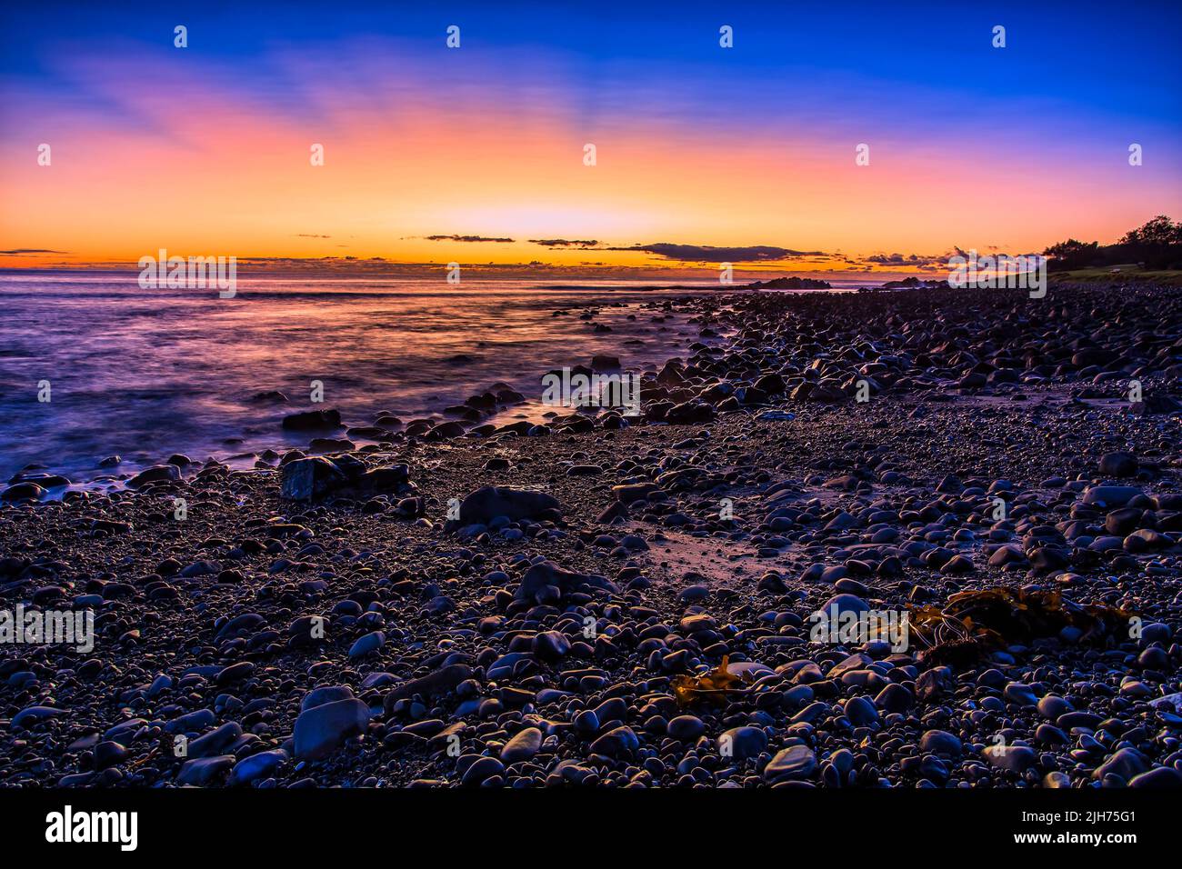 Spettacolare sorgere del sole colorato sull'orizzonte dell'oceano Pacifico al largo di Pebbly Beach nella città australiana di Forster. Foto Stock