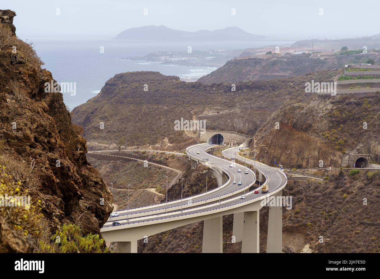 Strada su un enorme ponte che costeggia le montagne sul mare sull'isola di Gran Canaria. Spagna Foto Stock