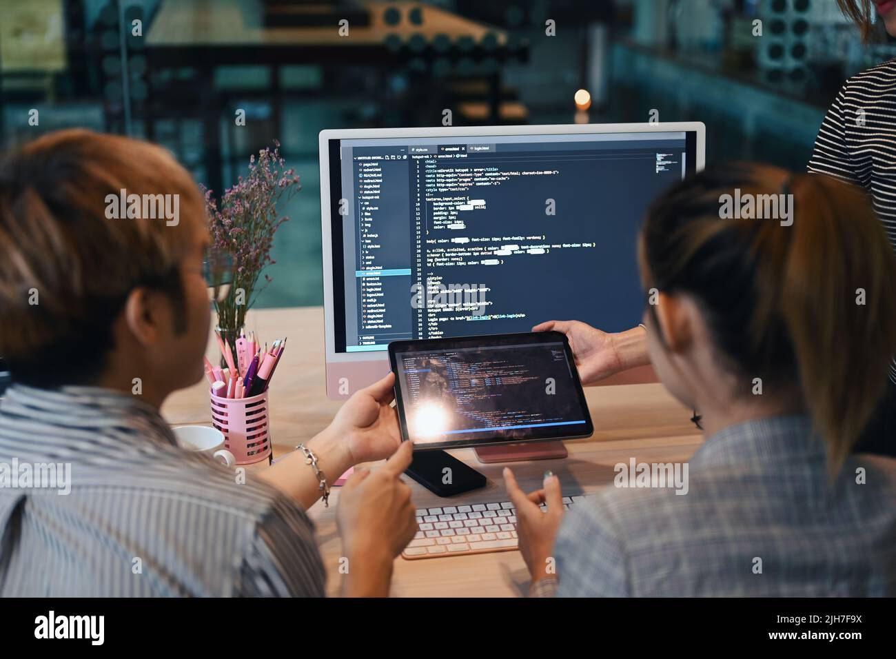 Vista posteriore del codice di programmazione del team di sviluppatori IT sullo schermo del computer e brainstorming per un nuovo progetto presso un ufficio moderno Foto Stock
