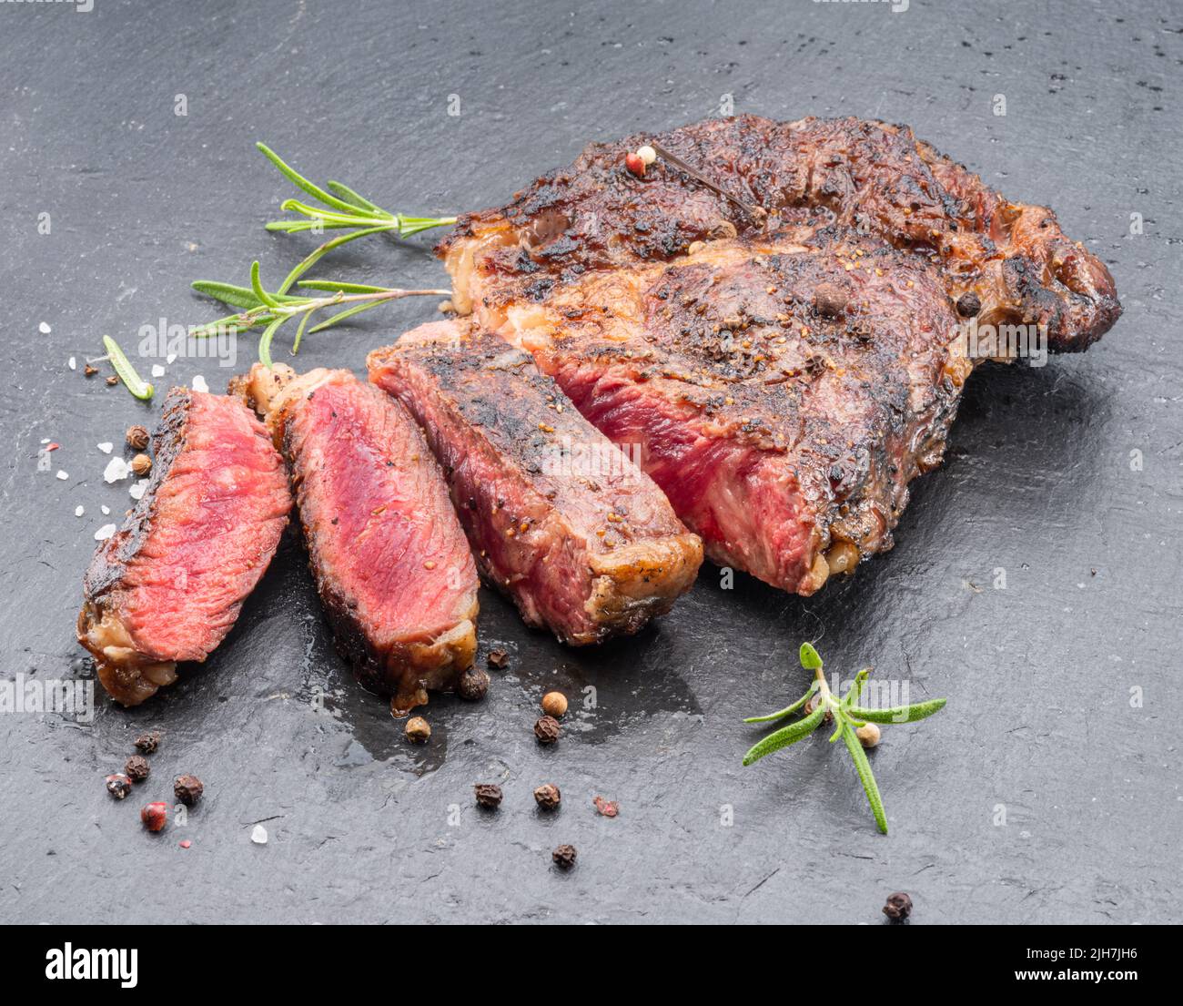 Bistecca di ribeye mediamente rara alla griglia su piastra di pietra grigia. Foto Stock