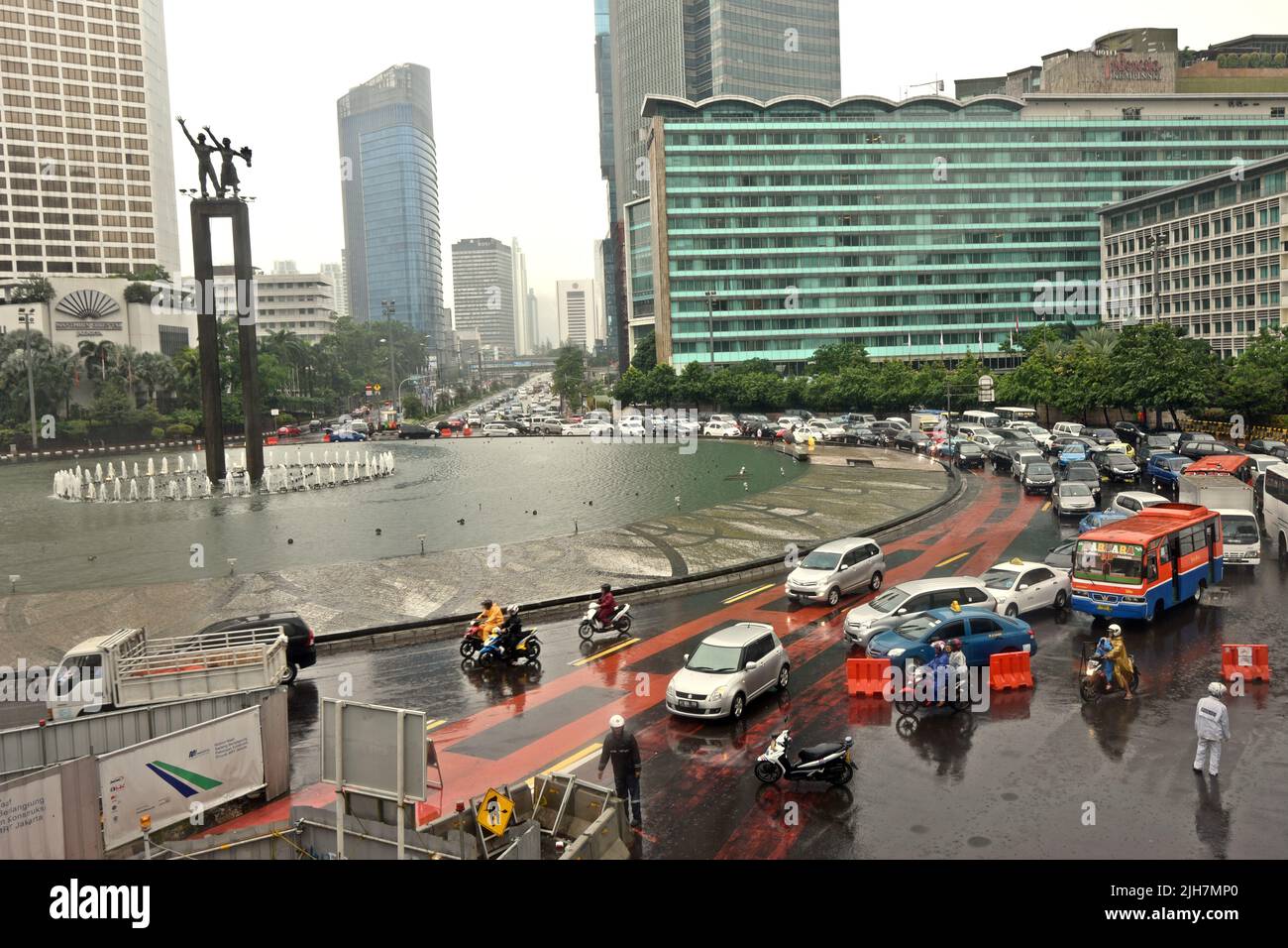 Traffico stradale a Bundaran HI (Hotel Indonesia Roundabout) in una giornata piovosa a Jakarta, Indonesia. Foto Stock