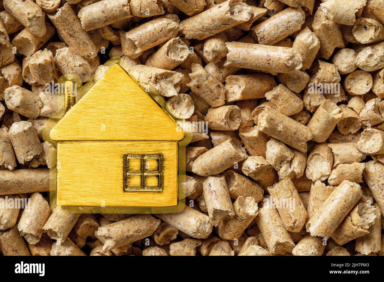 Piccola casa gialla su pellet di legno sfondo macro. Sawdus compattato come biocarburante organico. Riscaldamento ecologico alternativo, energia rinnovabile. Foto Stock