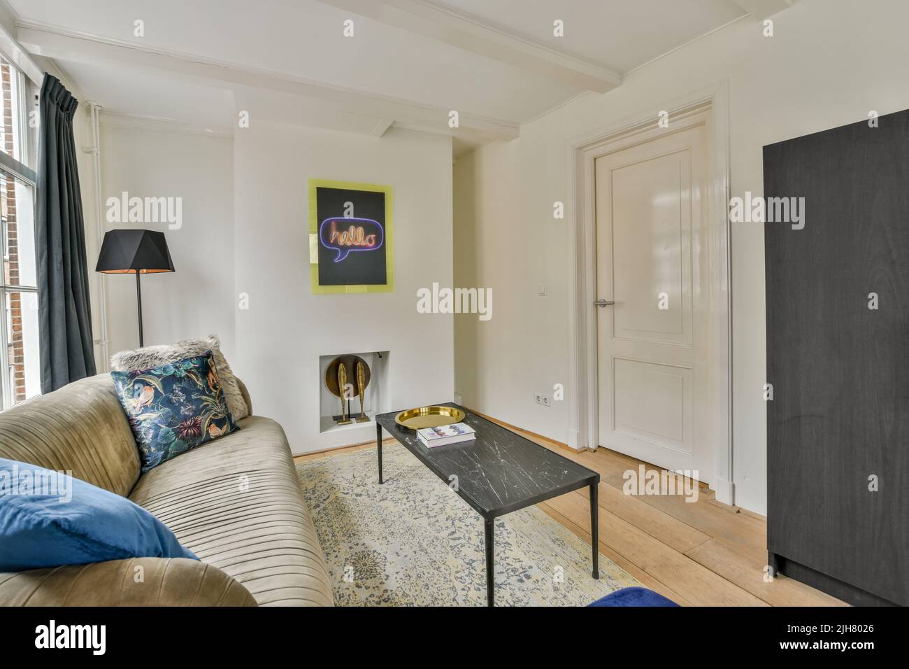 Comodo divano e posto su morbido tappeto vicino alle finestre in un accogliente e luminoso soggiorno in appartamento moderno Foto Stock