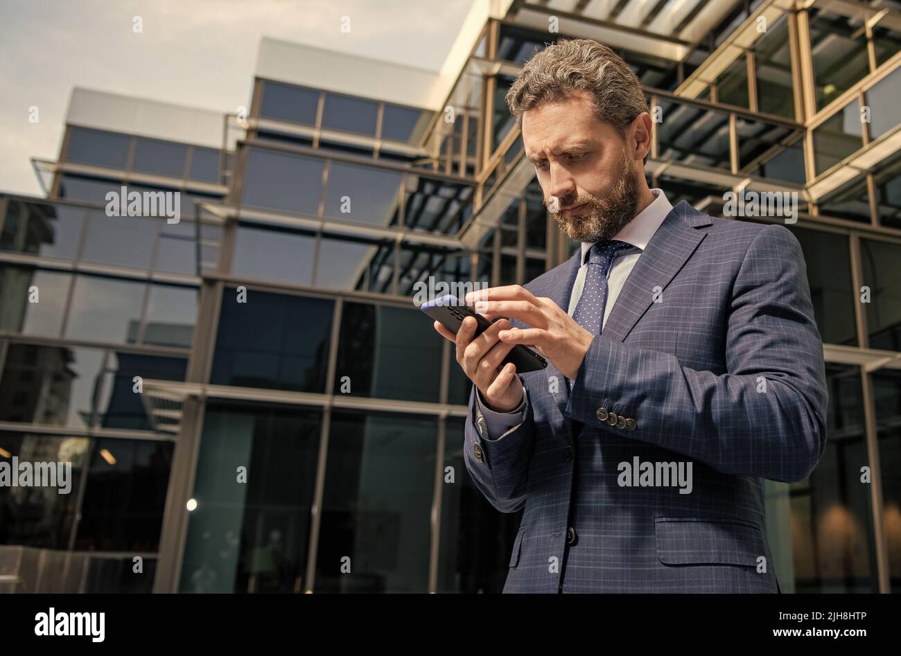 uomo d'affari maturo in formalwear chattando sul telefono all'aperto, spazio di copia, chat Foto Stock