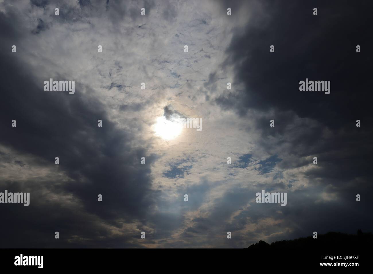 sole tra nuvole scure, scatto grandangolare Foto Stock