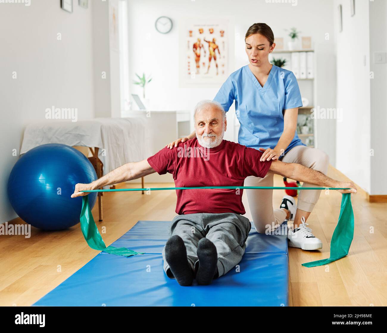 infermiera medico cura senior esercizio fisico terapia esercizio aiuto assistenza pensione casa fisioterapia strech band clinica terapista anziano uomo Foto Stock