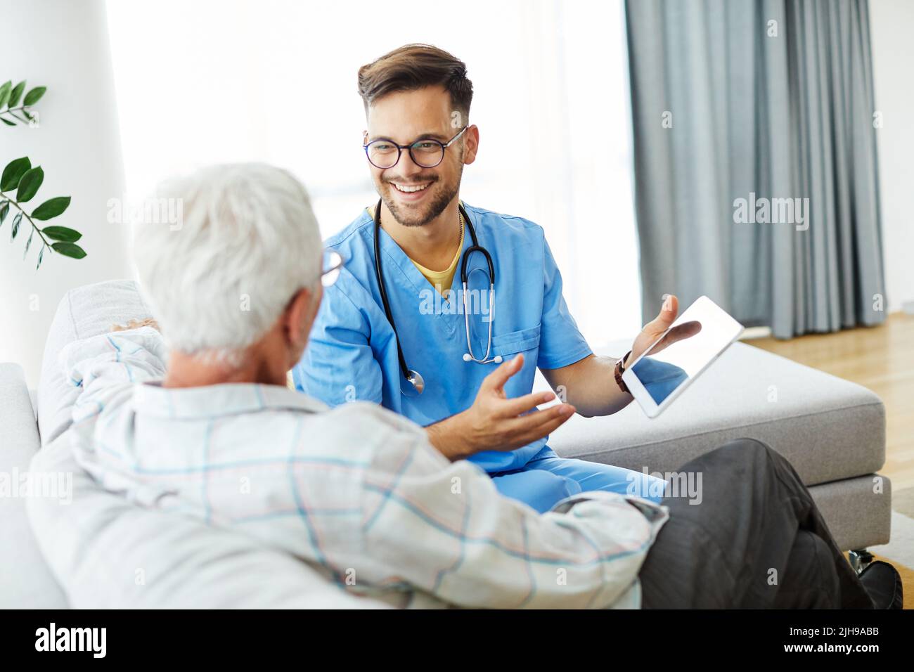 infermiera medico assistenza senior assistenza assistenza assistenza aiutare pensione casa tablet computer occupazione tecnologia Foto Stock