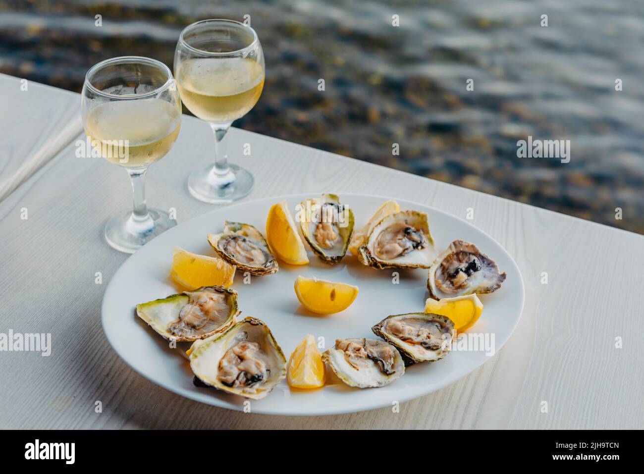 Ostriche appena pescate su un piatto e bicchieri di vite. Ristorante sulle rive della baia di Cattaro vicino alla fattoria di ostriche, Montenegro. Frutti di mare. Bella Foto Stock