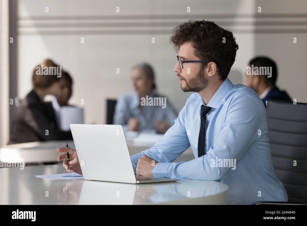 Serio giovane uomo d'affari che lavora al computer portatile in ufficio aperto Foto Stock
