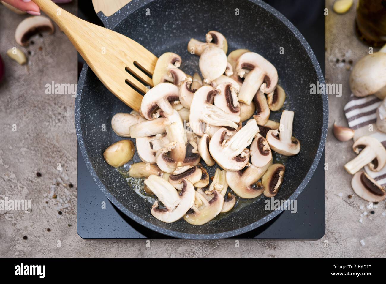 Affettati i funghi in una padella sul piano cottura a induzione della cucina domestica Foto Stock