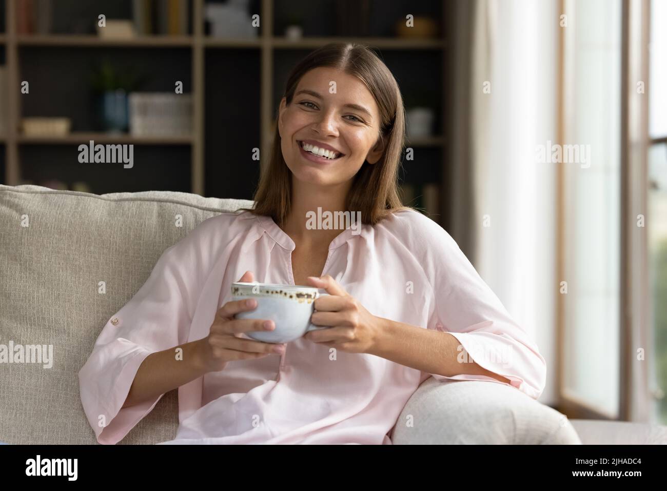 La donna che riposa su tiene la tazza di tè sorridere guardare la macchina fotografica Foto Stock