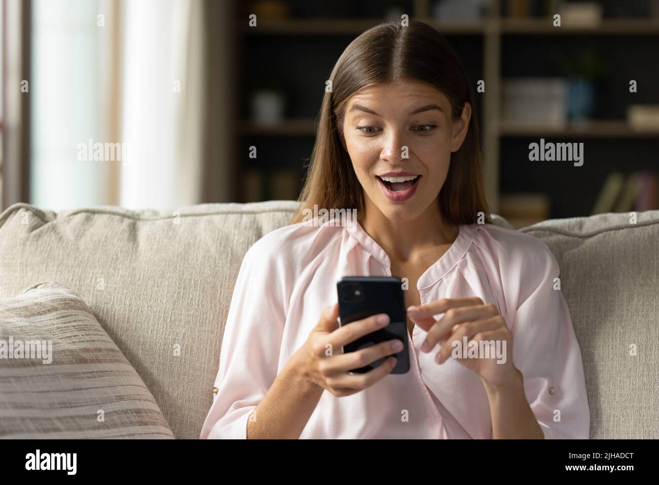 La donna tiene lo smartphone a guardare lo schermo leggere sms sembra stordito Foto Stock