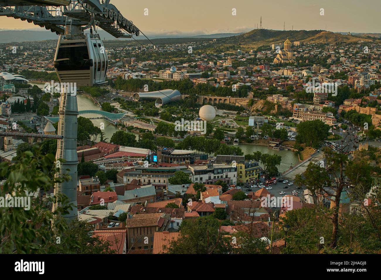 Tbilisi, Georgia tramonto Vista panoramica dalla cima della fortezza di Narikala che mostra il ponte della pace, Rike Park, fiume Kura e Cattedrale della Santissima Trinità Foto Stock
