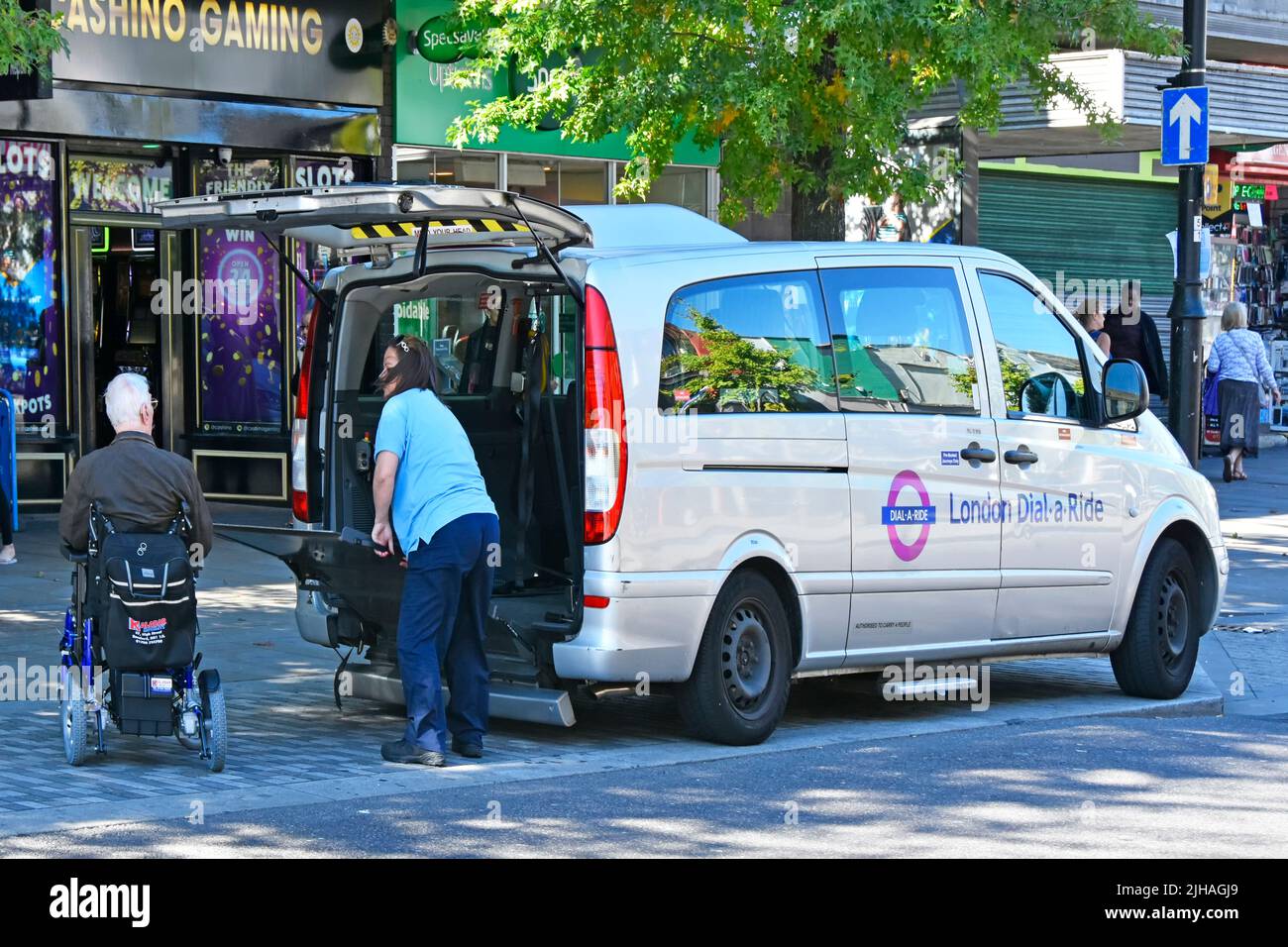 London Transport Dial-a-Ride servizio porta-a-porta gratuito per persone disabili autista che consegna l'uomo in sedia a rotelle a Romford shopping Street Inghilterra UK Foto Stock