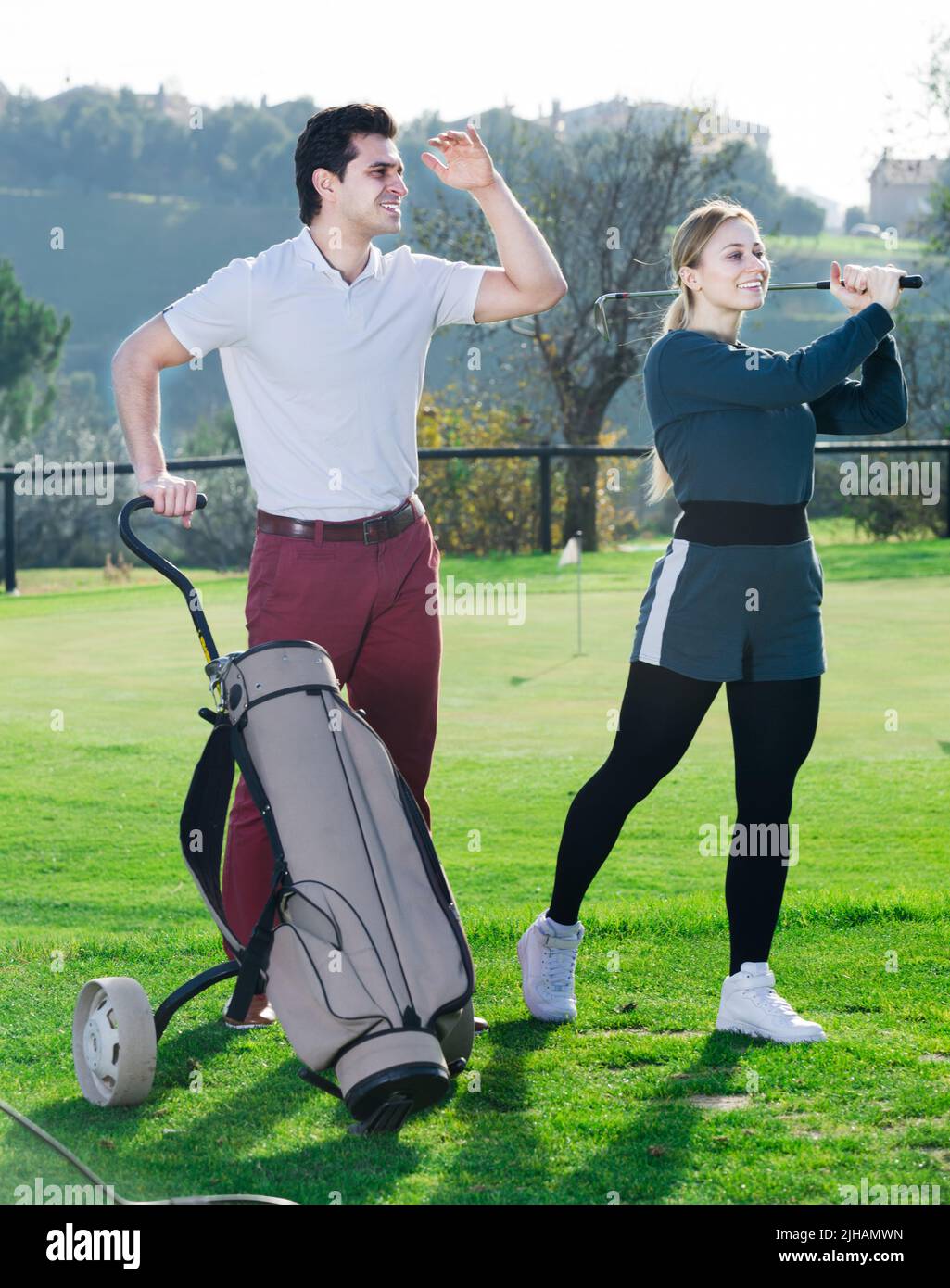 Uomo che guarda una ragazza di gioco golfer Foto Stock