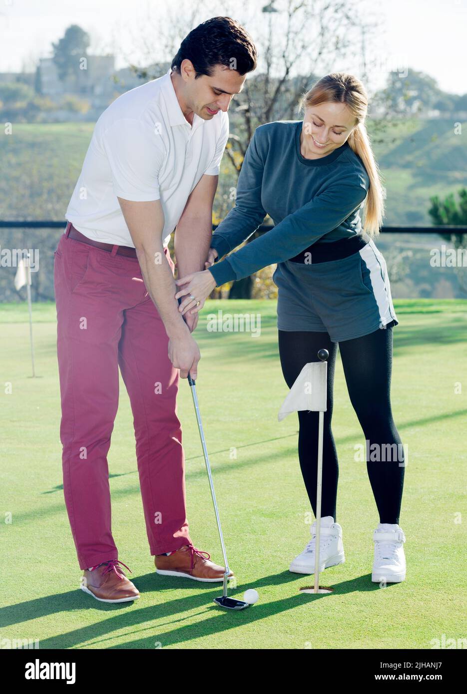 Donna golfer che addestrano l'uomo per giocare il golf Foto Stock